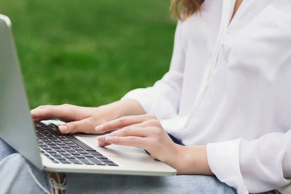 Kvinnan räcker att skriva på laptop tangentbord utomhus — Stockfoto