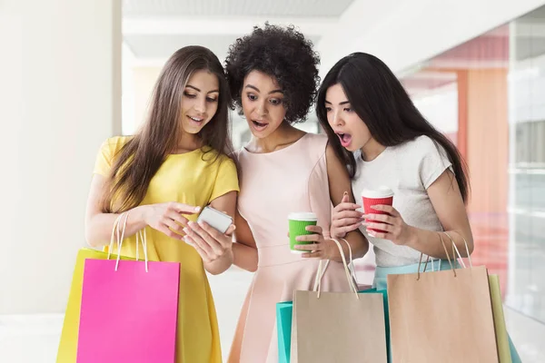 Mulheres emocionais usando smartphone enquanto faz compras no shopping — Fotografia de Stock