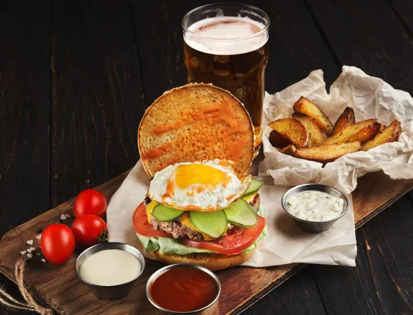 Burger and potatoes served with beer at restaurant — Stock Photo, Image