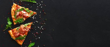 Dilim pizza ile siyah arka plan üzerine baharat