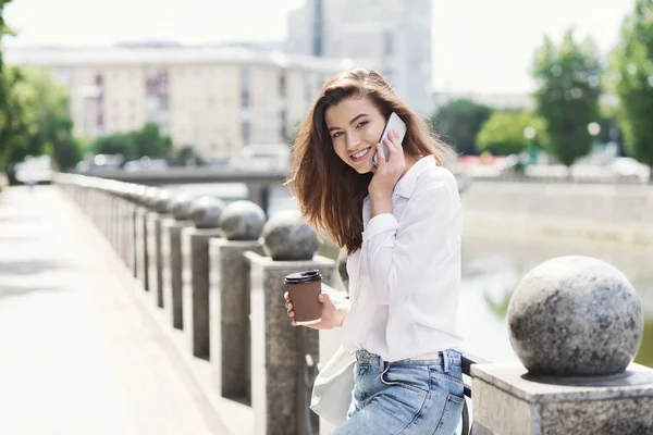 Hermosa chica sonriente hablando en el teléfono inteligente al aire libre — Foto de Stock