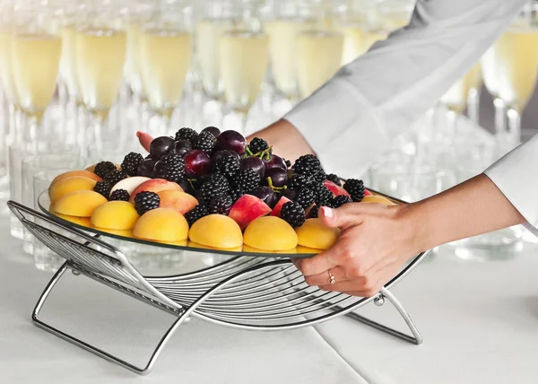 Camarero poniendo bandeja de frutas en la mesa en la fiesta —  Fotos de Stock