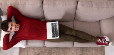 Laptop ile kanepede yatan adam üzerinde üstten görünüm