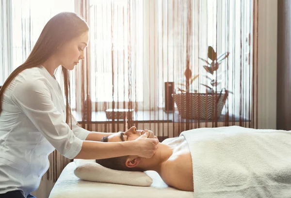 Cosmetologo facendo massaggio per giovane in salone — Foto Stock