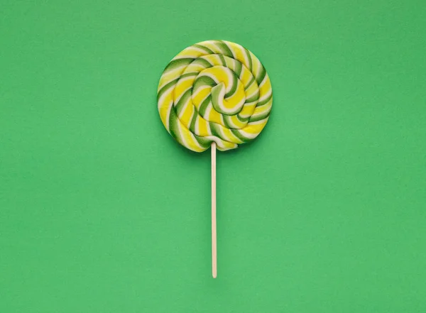 Spiral candy lollipop on green background, top view — Stock Photo, Image