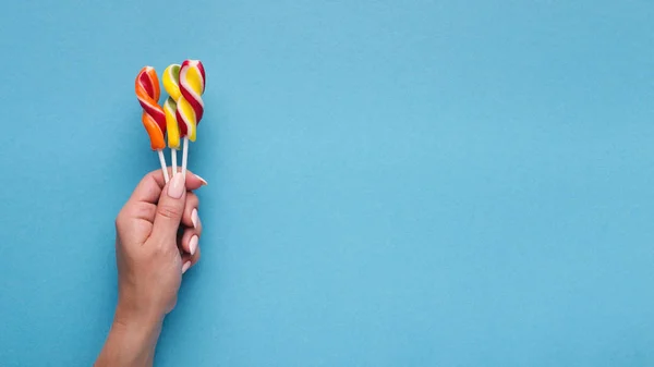 Woman holding candy lollipops on blue backgound