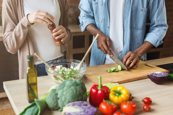 Svart par förbereder hälsosamma grönsaker sallad i köket — Stockfoto