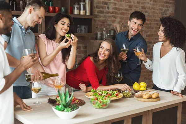 Groep vrienden drinken en eten in loft keuken — Stockfoto