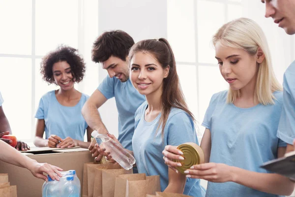 Voluntarios empacando alimentos y bebidas en bolsas de papel — Foto de Stock