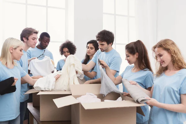 Unga volontärer grupp arbetar med kläder donation — Stockfoto