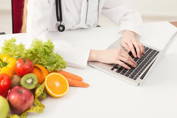 Unerkennbare Ernährungsberaterin arbeitet am Laptop — Stockfoto