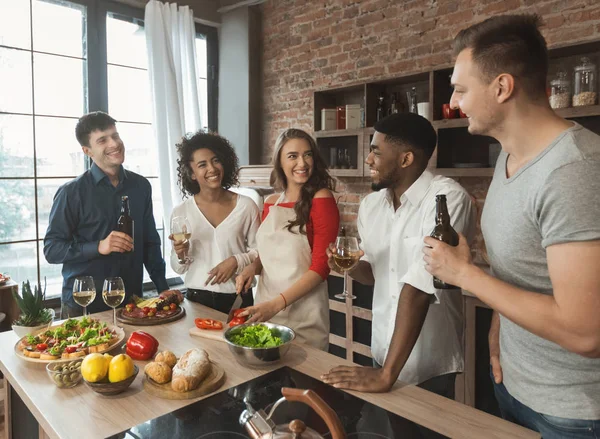 Amis heureux parler et boire tout en cuisinant à la cuisine — Photo