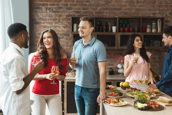 Multiraciale vrienden drinken en chatten in keuken — Stockfoto