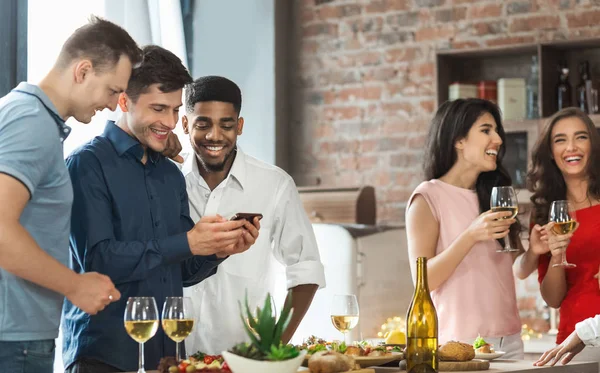 Amici maschi utilizzando smartphone mentre festeggiano a casa — Foto Stock