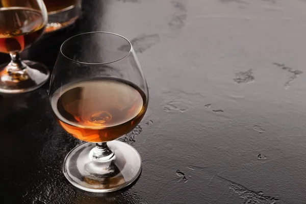 Cognac gedeelten in glas op zwarte achtergrond — Stockfoto