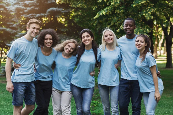 Группа молодых волонтеров, обнимающихся в парке — стоковое фото