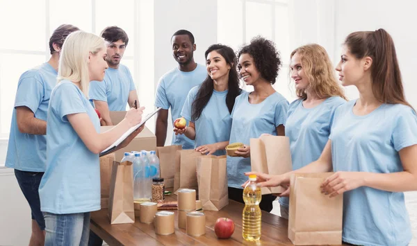 Voluntarios poniendo comida y bebidas en bolsas de papel — Foto de Stock