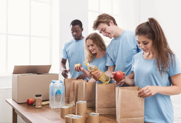 Voluntários embalando alimentos e bebidas em sacos de papel — Fotografia de Stock