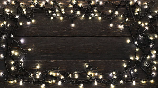 Frame of christmas garland lights on wooden background — Stock Photo, Image