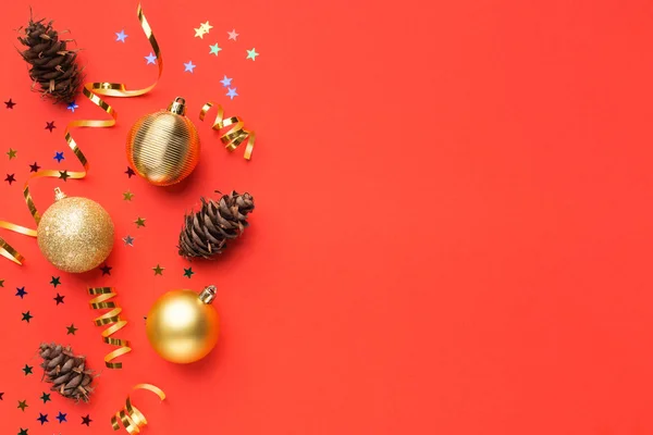 Різдвяні кульки та соснові шишки на червоному тлі — стокове фото