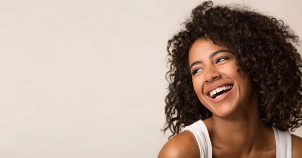 Смеющаяся афро-американка смотрит в сторону на светлом фоне — стоковое фото