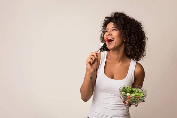 Senhora excitada comendo salada saudável sobre fundo claro — Fotografia de Stock