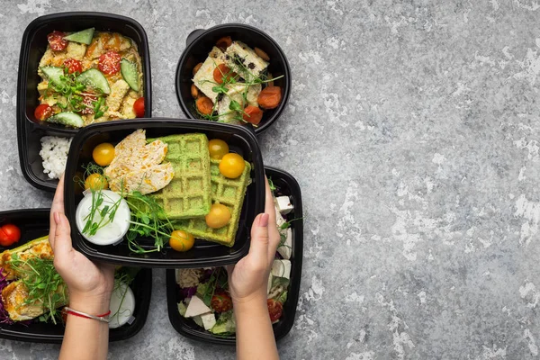 Envases de plástico con deliciosa comida sobre fondo gris — Foto de Stock