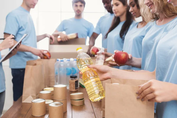 Voluntarios empacando alimentos y bebidas en bolsas de papel — Foto de Stock