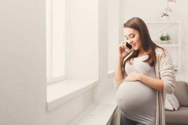 Gülümseyen hamile kadın onun smartphone üzerinde söz