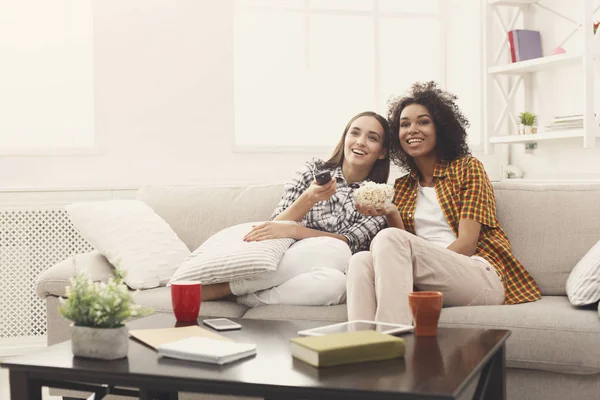 Lächelnde Freundinnen, die zu Hause fernsehen — Stockfoto