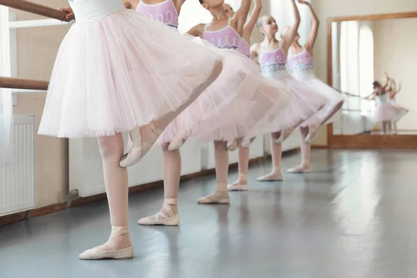 Chicas entrenando movimientos de baile cerca de la barra de ballet —  Fotos de Stock