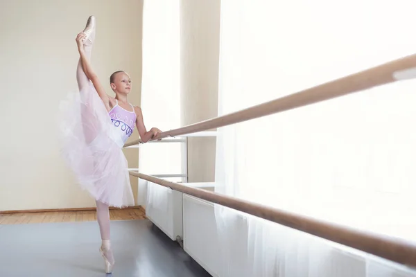 Ballerina in tutu stretching leg in vertical split in class — Stok Foto