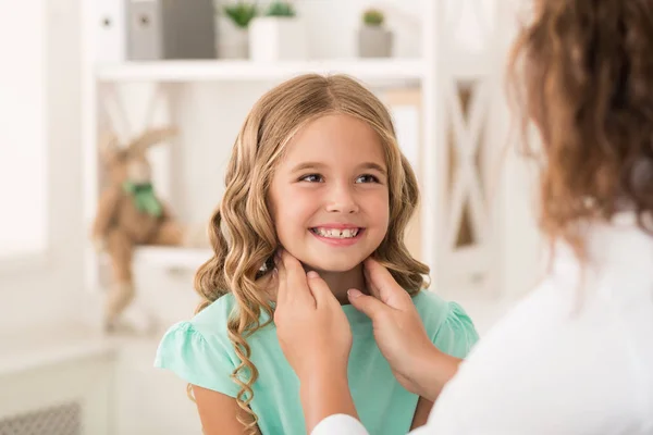 Positives Mädchen starrt Ärztin an, die ihre Mandeln kontrolliert — Stockfoto