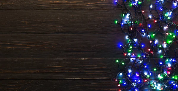 Kleurrijke Kerstverlichting op donkere houten achtergrond — Stockfoto