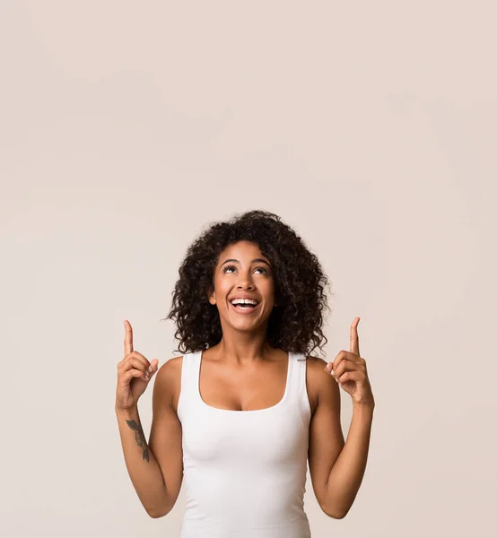 Excited african-american woman pointing up, copy space