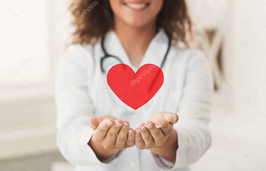 Doctor holding red heart in cupped hands