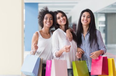 Güzel kadınlarla üç renkli çanta alışveriş merkezinde yürüyüş