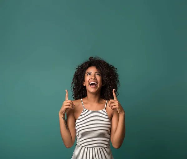 Lachende afrikanisch-amerikanische Frau zeigt mit dem Finger nach oben, kopiert Raum — Stockfoto