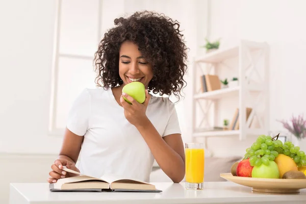 Donna afro-americana che legge libro e mangia mela — Foto Stock