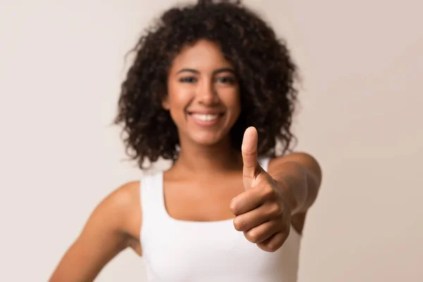 Гарненька чорна жінка показує великий палець на світлому фоні — стокове фото