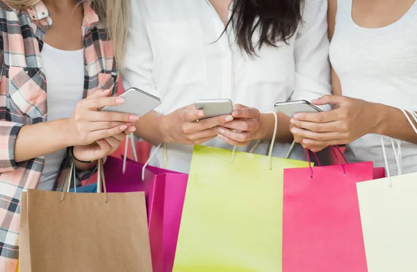 Mujeres jóvenes con teléfonos inteligentes y bolsas de compras — Foto de Stock