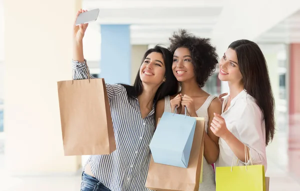 Jovens mulheres felizes com smartphone tirando selfie no shopping — Fotografia de Stock