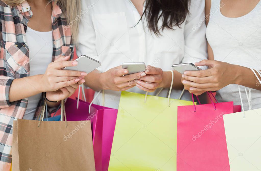 Young women with smartphones and shopping bags