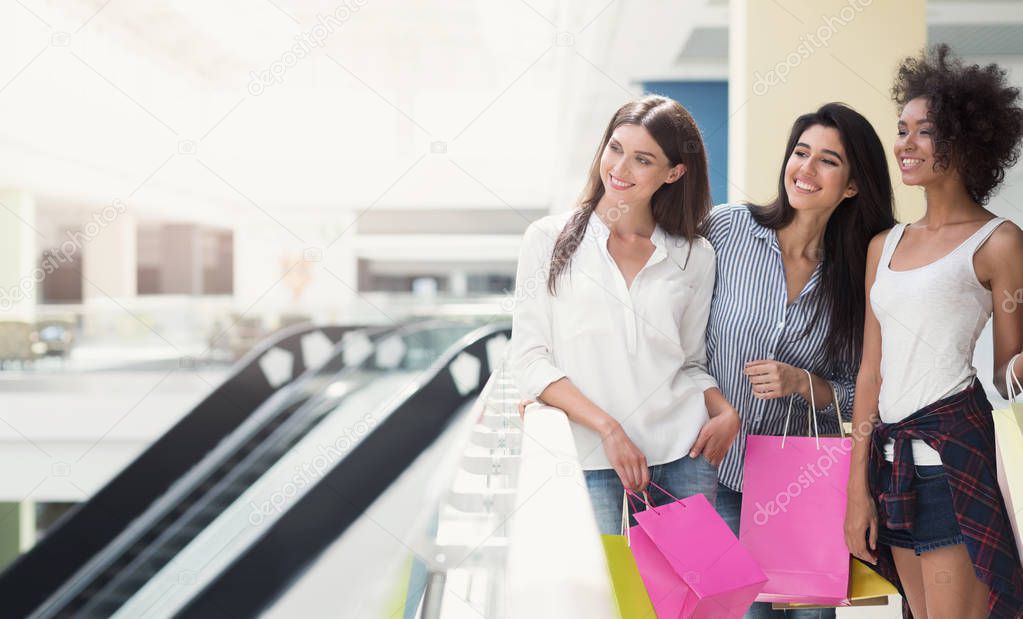 Happy women walking in mall with shopping bags