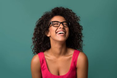 Mavi arka plan üzerinde gülerek mutlu bir Afrikalı-Amerikalı kadın