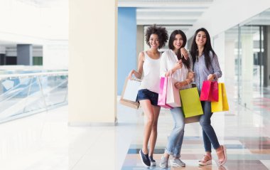 Alışveriş merkezinde alışveriş torbaları ile neşeli kızlar