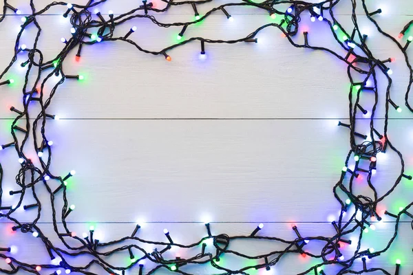 Glowing colourful christmas lights on wooden background — Stock Photo, Image