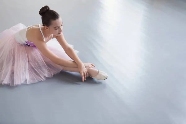 Young ballerina in pointe shoes stretching on floor — Stock Photo, Image