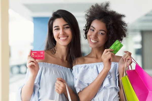 Dos mujeres atractivas felices con tarjetas de crédito de compras en el centro comercial — Foto de Stock