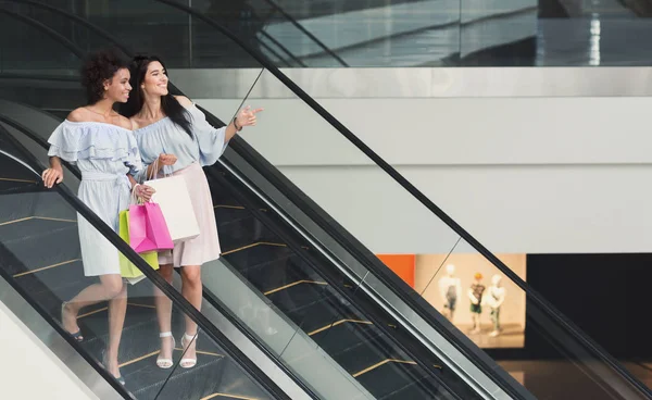 Femmes heureuses pointant quelque chose sur l'escalator — Photo